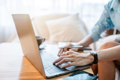 Midsection of woman using laptop at home