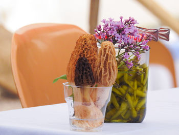 Close-up of champignonsin glass on table with flowers and pickle 