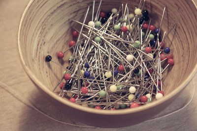 High angle view of colorful straight pins in bowl on table