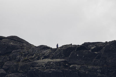 Low angle view of man standing on cliff against sky