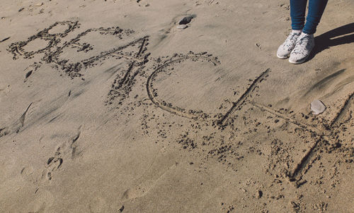 Low section of person standing on sand at beach