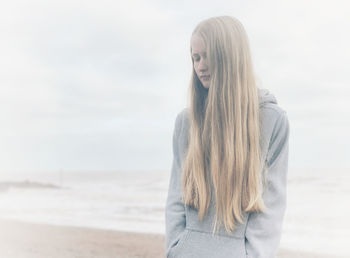 Young woman standing at beach against sky