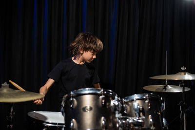 Side view of man playing drum at home