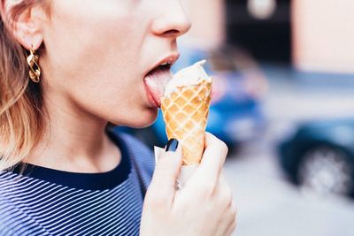 Midsection of woman licking ice cream
