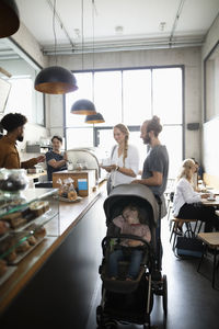 Smiling parents with daughter in stroller ordering at coffee shop