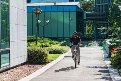 Businessman riding bicycle on road by buildings