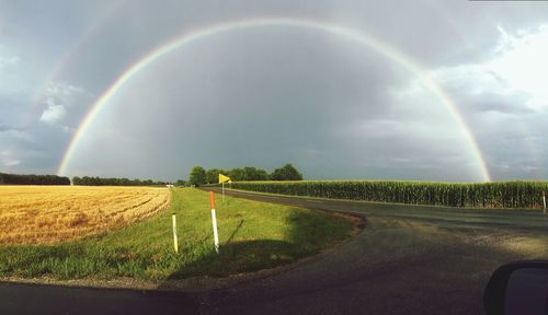 Scenic view of field against rainbow in sky