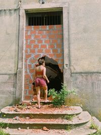 Portrait of young woman standing against wall