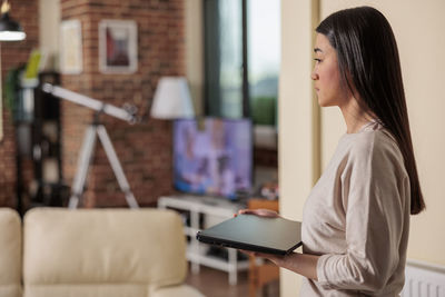 Side view of woman holding laptop