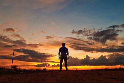 Rear view of silhouette man standing on street during sunset