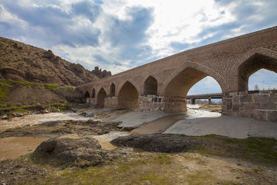 Arch bridge over river against sky