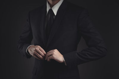 Midsection of man standing against black background