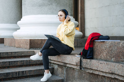 Outdoor portrait of happy student girl, young woman listening to audio lessons