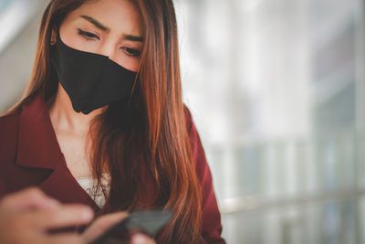 Low angle view of woman wearing mask using smart phone
