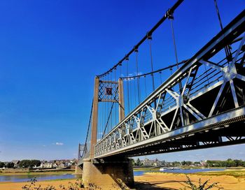 Low angle view of suspension bridge against blue sky