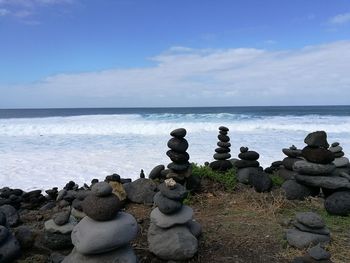 Stack of pebbles by sea against sky