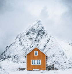 House on snow covered mountain against sky