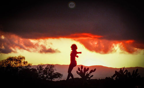 Silhouette woman standing on field against sky during sunset