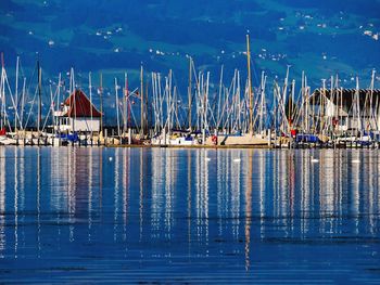 Sailboats moored at harbor against blue sky