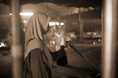 Rear view of man holding umbrella at night