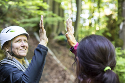 Close-up of friends high-fiving in forest