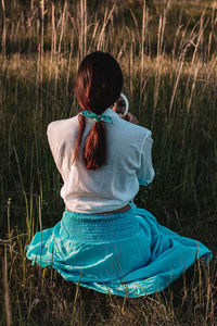 Rear view of woman sitting on field