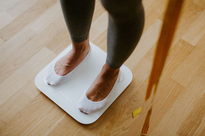 Low section of person standing on wooden floor at home