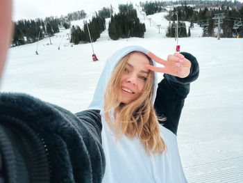 Happy young woman skier taking selfie hiking mountains. girl smiling makes selfie in ski clothing