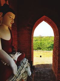 Full length of young woman sitting at archway