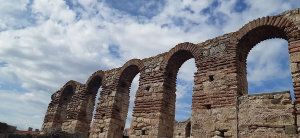 Low angle view of old ruin building against cloudy sky