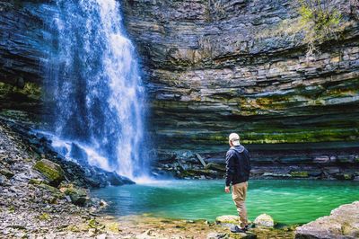 Man standing in front of waterfall