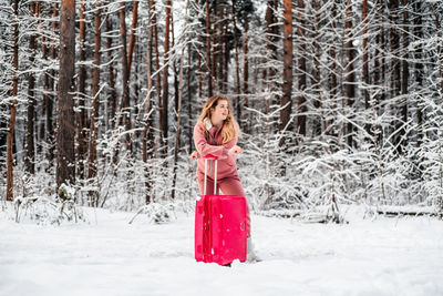 Woman standing in snow covered forest