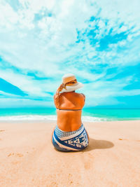 Man wearing sunglasses on beach against sky