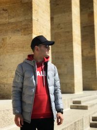 Young man wearing sunglasses standing against built structure