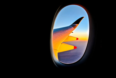 Close-up of airplane wing against sky during sunset