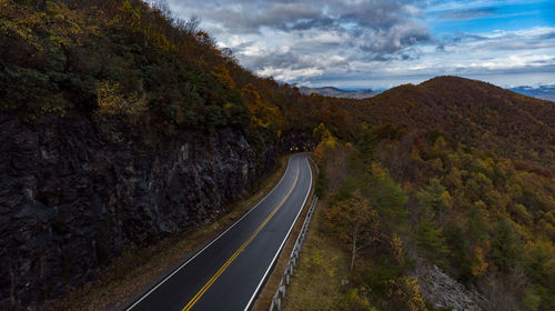 Empty road leading towards mountains against sky