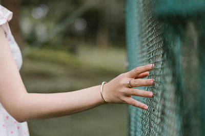 Close-up of woman touching fence