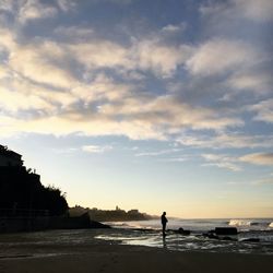 Silhouette man on beach against sky during sunset