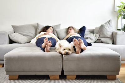 Mother and daughter relaxing with dogs relaxing on sofa at home
