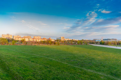 Scenic view of field by buildings against sky