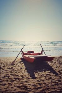 Boat moored on beach against clear sky
