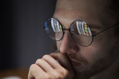 Close-up of young man smoking cigarette against black background