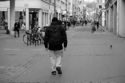Rear view of man walking on street in city