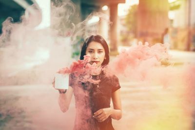 Portrait of young woman smoking outdoors