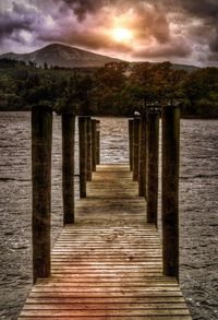 Pier on lake against cloudy sky