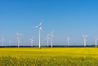 Wind power plants in a blooming rapeseed field seen in rural germany