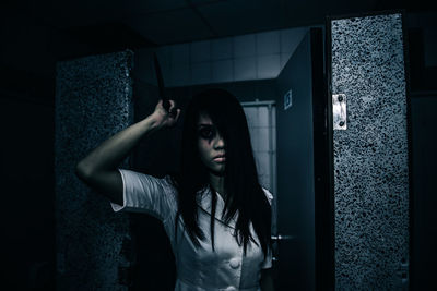 Portrait of young woman standing against wall