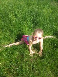 High angle view of playful girl sitting on grassy field during summer