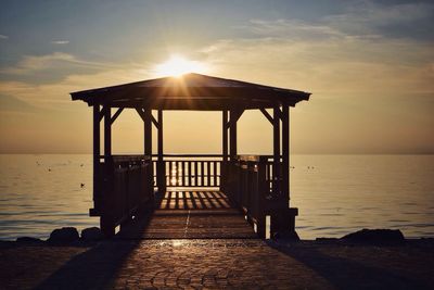 Pier over sea against sky during sunset