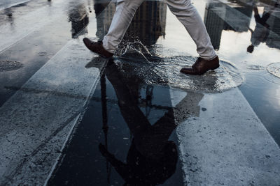 Low section of man walking on wet street